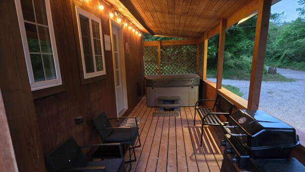 Een houten terras met een barbecue, zitplaatsen en een hottub.