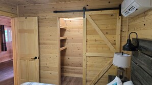 Een houten interieur met een bed, nachtkastje, lamp en kledingkast.