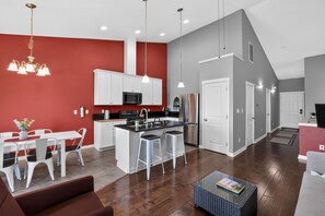 Une cuisine moderne avec des meubles blancs, un îlot central et des appareils électroménagers en acier inoxydable.