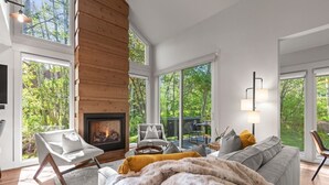 A modern living room with a fireplace, large windows, and a cozy seating area. - 2 Min Walk To Ski*Hot Tub, Pool, Gym, Modern (Park City)