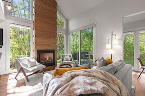 A modern living room with a fireplace, large windows, and a cozy seating area. - 2 Min Walk To Ski*Hot Tub, Pool, Gym, Modern (Park City)