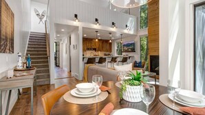 A spacious dining area with a wooden table set for a meal, a kitchen in the background, and a staircase leading to an upper level. - 2 Min Walk To Ski*Hot Tub, Pool, Gym, Modern (Park City)