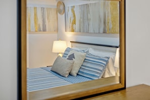 A bed with striped bedding, a lamp, and a wall art piece. - Charming Buckhead 1 BR Unit Queen TheraPedic Bed (Atlanta)