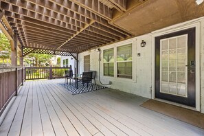 A covered porch with a wooden floor, a black and white rug, two chairs, and a door with a window. - Charming Buckhead 1 BR Unit Queen TheraPedic Bed (Atlanta)