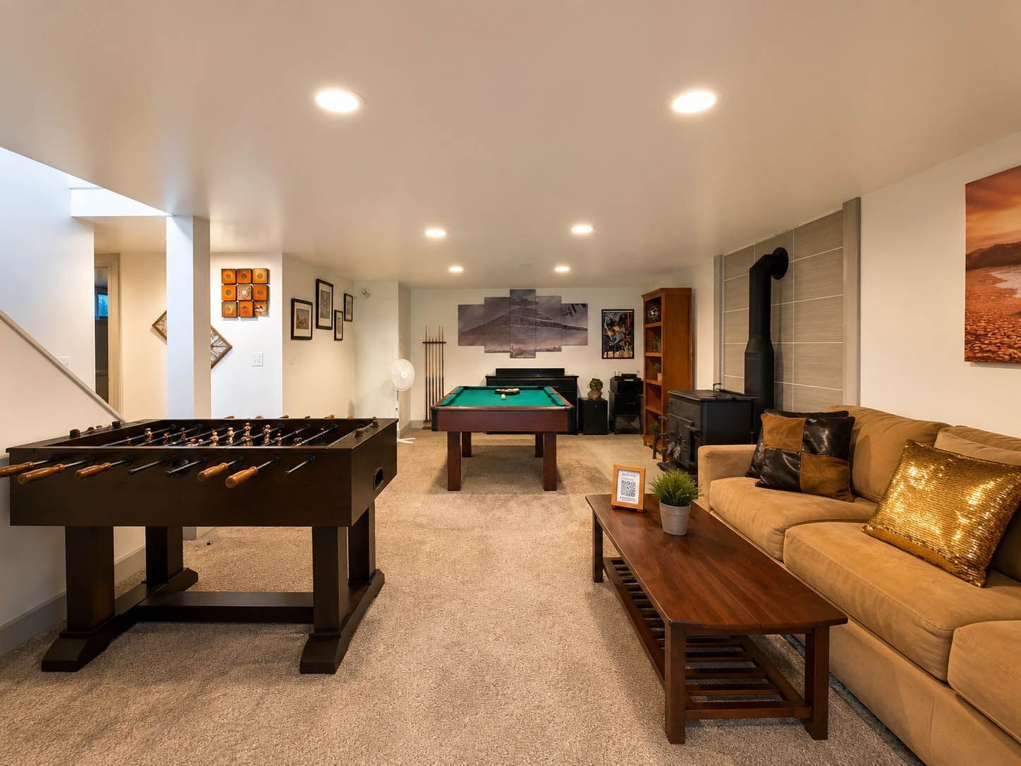 A cozy living room with a foosball table, a pool table, and a sofa.