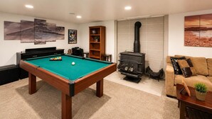 A pool table in a room with a sofa and a fireplace.
