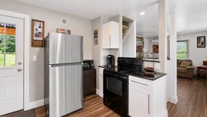 A modern kitchen with a stainless steel refrigerator, a black stove, and white cabinetry.