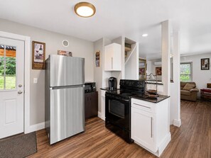A modern kitchen with a stainless steel refrigerator, a black stove, and white cabinetry.