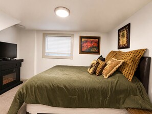 Un dormitorio con cama, televisión, chimenea y obras de arte en las paredes.