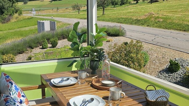 Ein Esstisch, gedeckt für ein Essen, mit Blick auf eine grüne Landschaft.