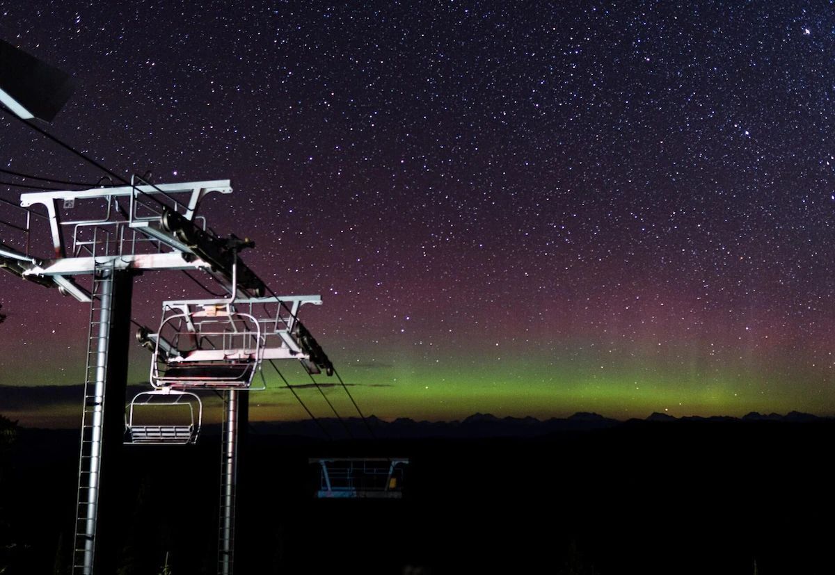 Cielo nocturno con estrellas y la aurora boreal.