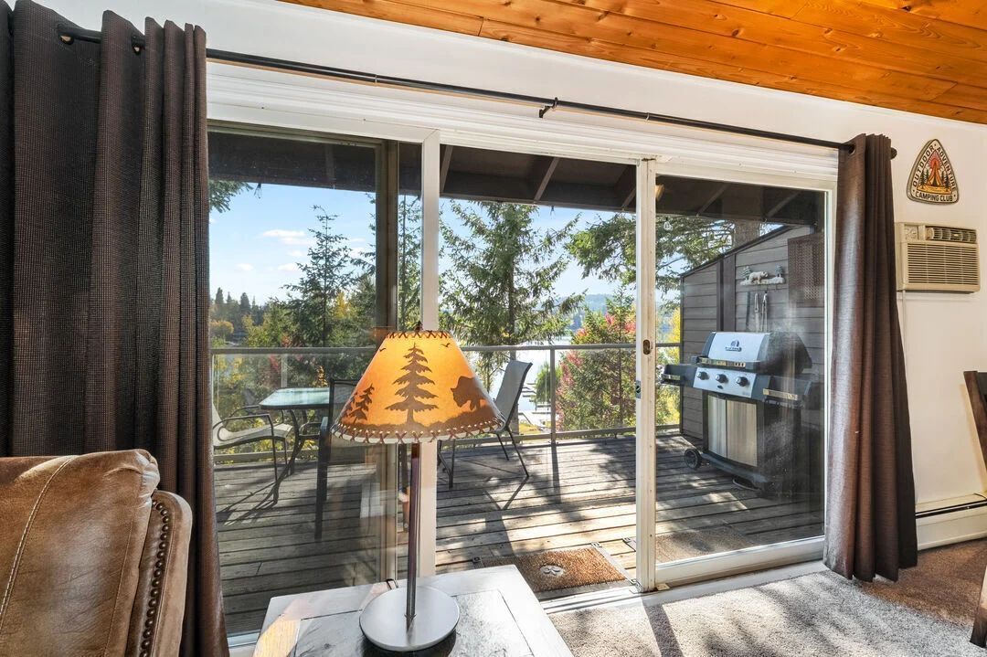 Sliding glass doors lead out to a wooden deck with a grill and lake views.