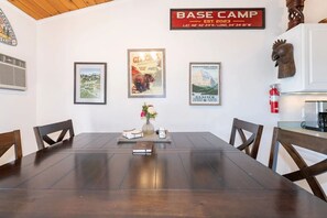 A dark wood dining table set beneath walls decorated with national park artwork. - Whitefish Lake Condo w/ Dock & Pool (Whitefish)
