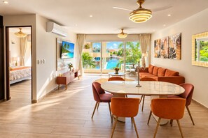 A modern hotel room with a dining area, a pool view, and a large window. - Marina view 3BR pool 7min walk to beach (Puerto Aventuras)