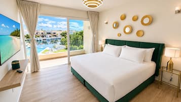 A hotel room with a large bed, a TV, a view of a pool and boats, and a balcony with curtains.