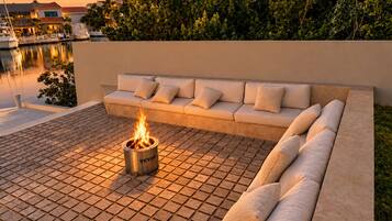 Un área de estar exterior moderna con una chimenea, una piscina y vistas a un área residencial.