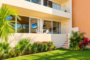 A modern two-story house with a balcony, large windows, and a well-maintained garden. - Marina view 3BR pool 7min walk to beach (Puerto Aventuras)