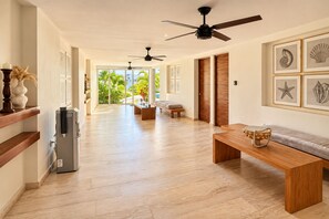 A spacious hallway with a ceiling fan, a refrigerator, a wooden bench, and framed artwork on the walls. - Marina view 3BR pool 7min walk to beach (Puerto Aventuras)