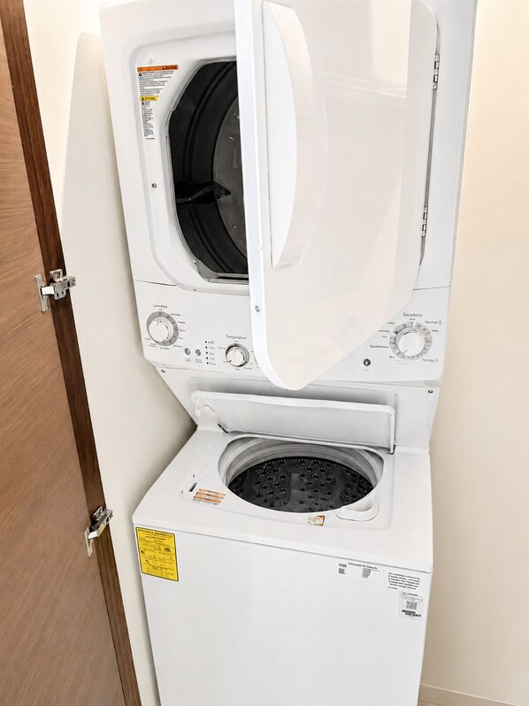 A front-loading washing machine with a control panel, a door, and a label on the front. - Marina view 3BR pool 7min walk to beach (Puerto Aventuras)