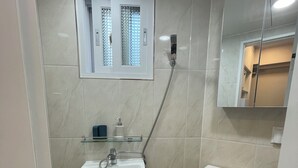 Ein Badezimmer mit weißem Waschbecken, Toilette, Dusche und Spiegel.