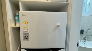 Ein weißer Kühlschrank mit integrierter Mikrowelle darüber, einem Wasserspender und einem Aufkleber, der ihn als LG Smart Care Kühlschrank kennzeichnet.