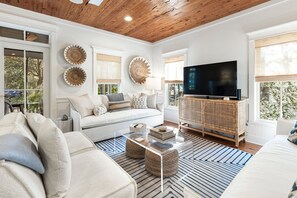 A modern living room with a sofa, coffee table, and TV. - Newly Renovated Cottage on 30a - Fin and Tonic (Seacrest)