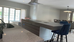 A modern kitchen with a large island, bar stools, and a dining area with chairs. - Prime  Bethesda Location Easy Access to DC (Bethesda)