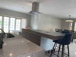 Eine moderne Küche mit einer großen Kochinsel, Barhocker und einem Essbereich mit Stühlen.