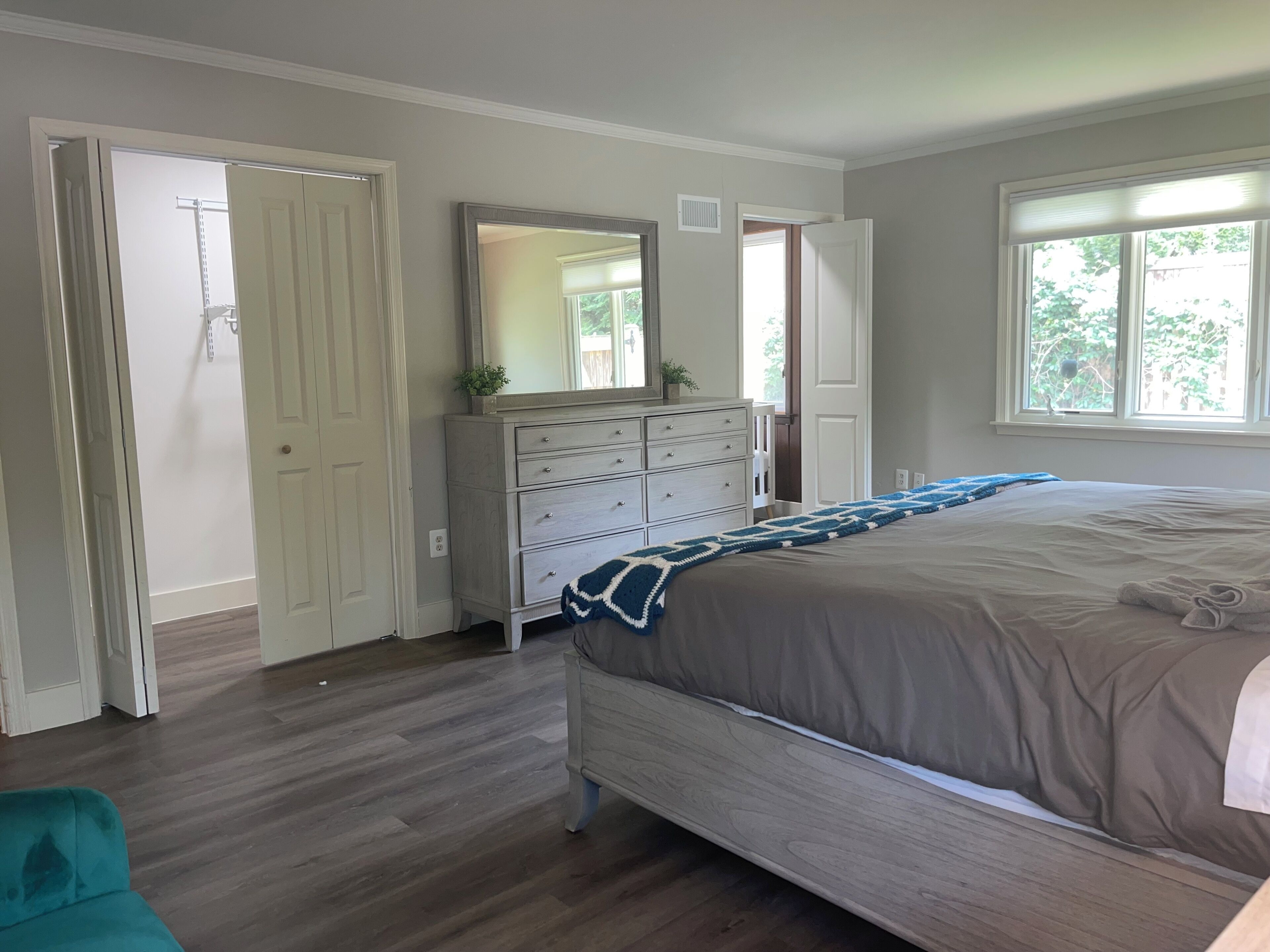 Une chambre à coucher avec un lit, une commode, un miroir et une fenêtre.