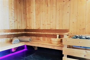 Un sauna en bois avec des bancs, un bassin en pierre et une serviette.