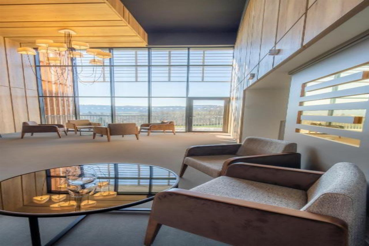 A modern interior with a large window, a round glass table, and several sofas.