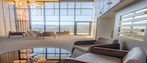 A modern interior with a large window, a round glass table, and several sofas.