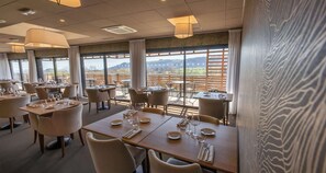 Un ristorante con tavoli apparecchiati, ampie finestre che offrono una vista e un design d'interni moderno.