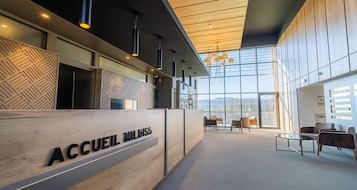 A reception area with a wooden reception desk labeled 'ACCUEIL MILDIS' and a seating area with chairs and a table.