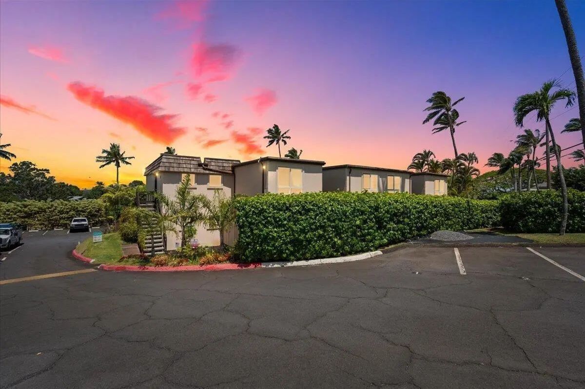 Exterior of the residential complex and parking lot beneath a colorful sunset sky.
