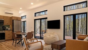Eine moderne Küche mit Einbauofen, ein Essbereich mit rundem Tisch und Stühlen, ein großer Sitzsack und eine Couch.