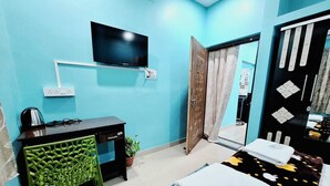 Una habitación con cama, escritorio, televisor y puerta.