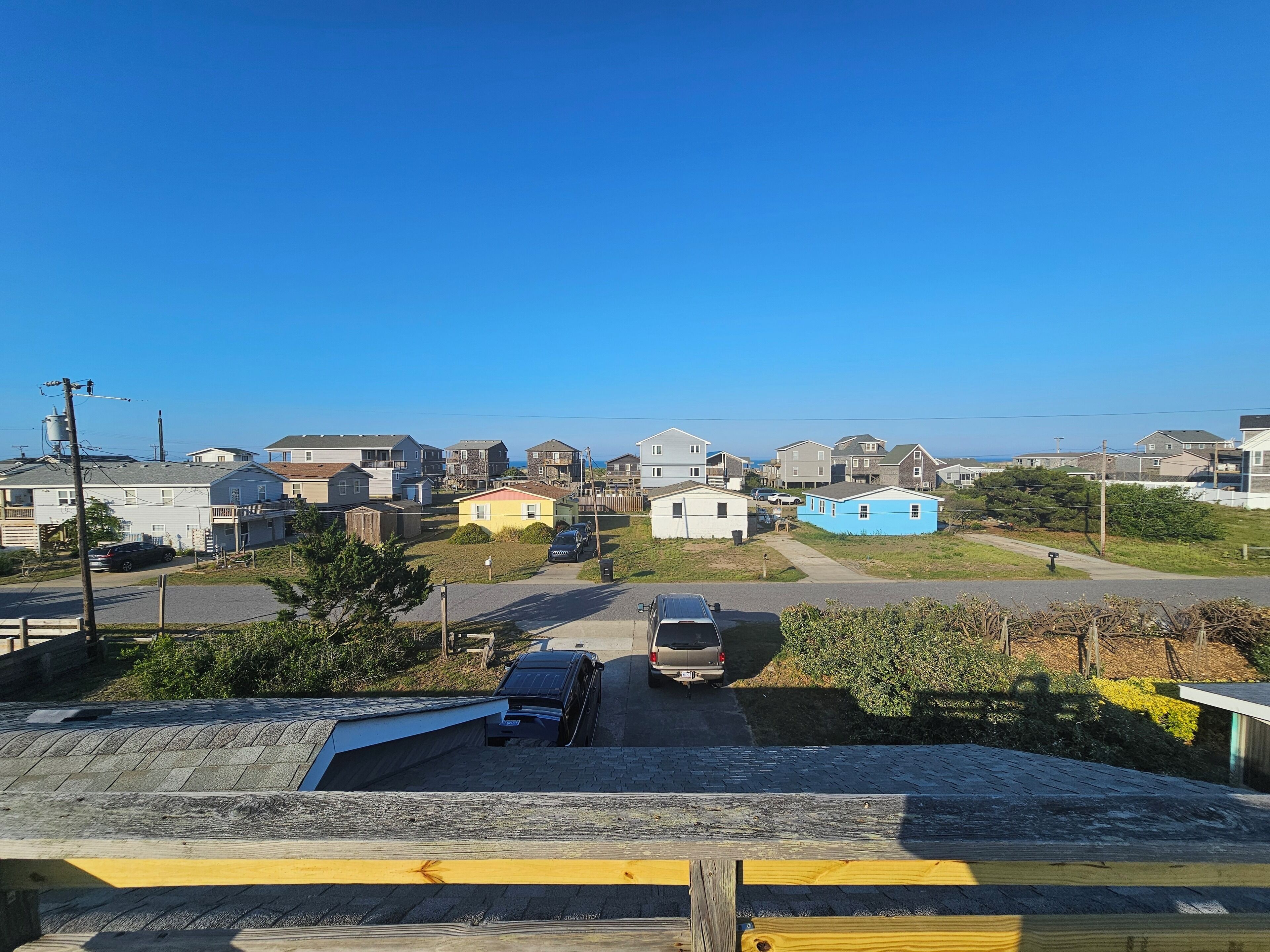 A residential area with houses, a road, and parked cars.
