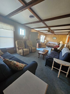 A cozy living room with a sofa, armchairs, a coffee table, and a dining area. - Nostalgic 1960's beach house in Kill Devil Hills close to beach access. (Kill Devil Hills)