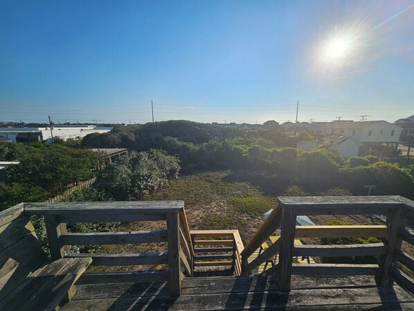 A wooden staircase leading to a viewing platform with a clear view of a beach and buildings in the distance. - Nostalgic 1960's beach house in Kill Devil Hills close to beach access. (Kill Devil Hills)