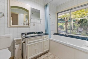 Ein Badezimmer mit Waschbecken, Spiegel, Schrank und Badewanne.