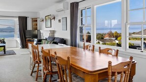 A spacious dining area with a large wooden table and chairs, a television, and a fireplace. - Relax and Recharge overlooking Lake Taupo (Taupō)