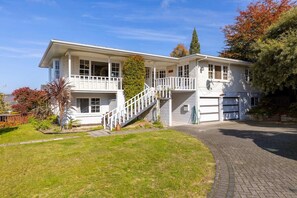 Ein zweistöckiges Haus mit Veranda, Treppe und Garage.