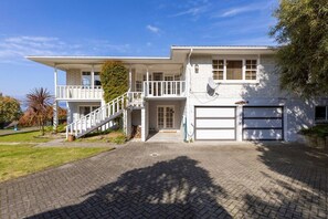 Een huis met twee verdiepingen, een overdekte veranda, een garage en een trap naar de bovenverdieping.