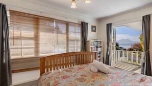 A bedroom with a bed, a bookshelf, and a balcony with a view. - Relax and Recharge overlooking Lake Taupo (Taupō)