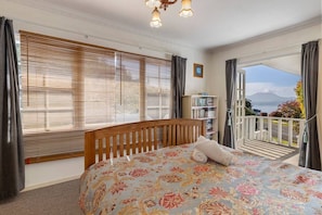 Ein Schlafzimmer mit Bett, einer Bücherwand und einem Balkon mit Aussicht.