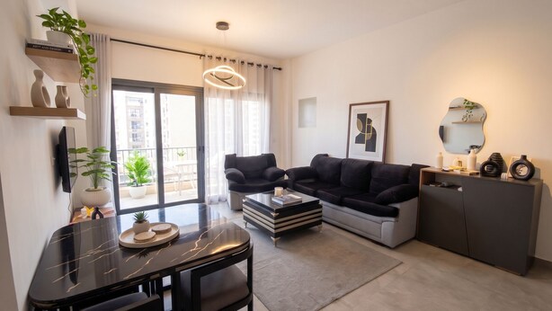 Uma sala de estar moderna com um sofá, uma mesa de centro, uma TV e uma área de jantar com mesa e cadeiras.