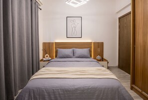 Ein Schlafzimmer mit Bett, Vorhängen, Kopfteil, Nachttisch und einem Kleiderschrank. Ein gerahmtes Bild ist ebenfalls zu sehen.