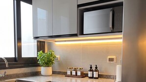 Cozinha moderna com eletrodomésticos de aço inoxidável, micro-ondas embutido e uma planta em vaso sobre a bancada.