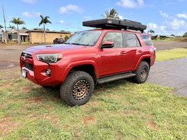 A red SUV parked on a grassy area with a building in the background.
